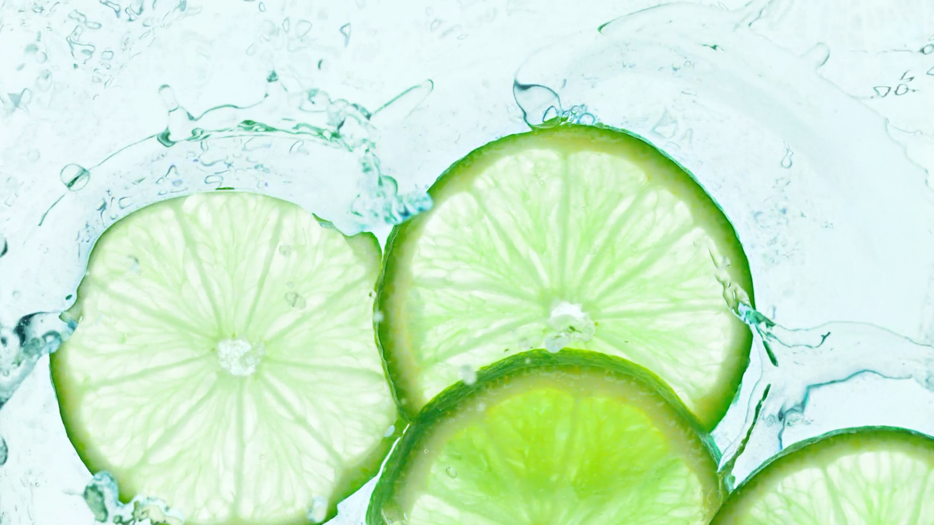 Lime slices splashing in water.
