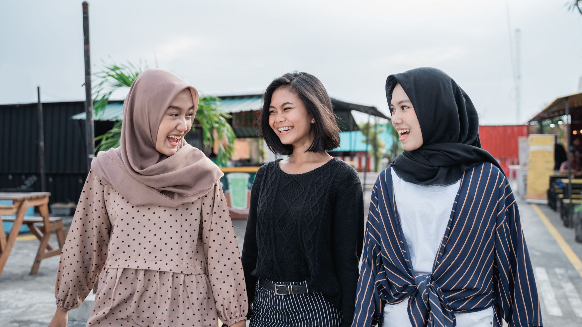 Tiga wanita tersenyum dan berjalan di luar ruangan.