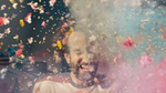 Laughing man surrounded by colorful flower petals.