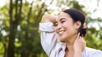 Smiling person in a white shirt outdoors with trees in background.