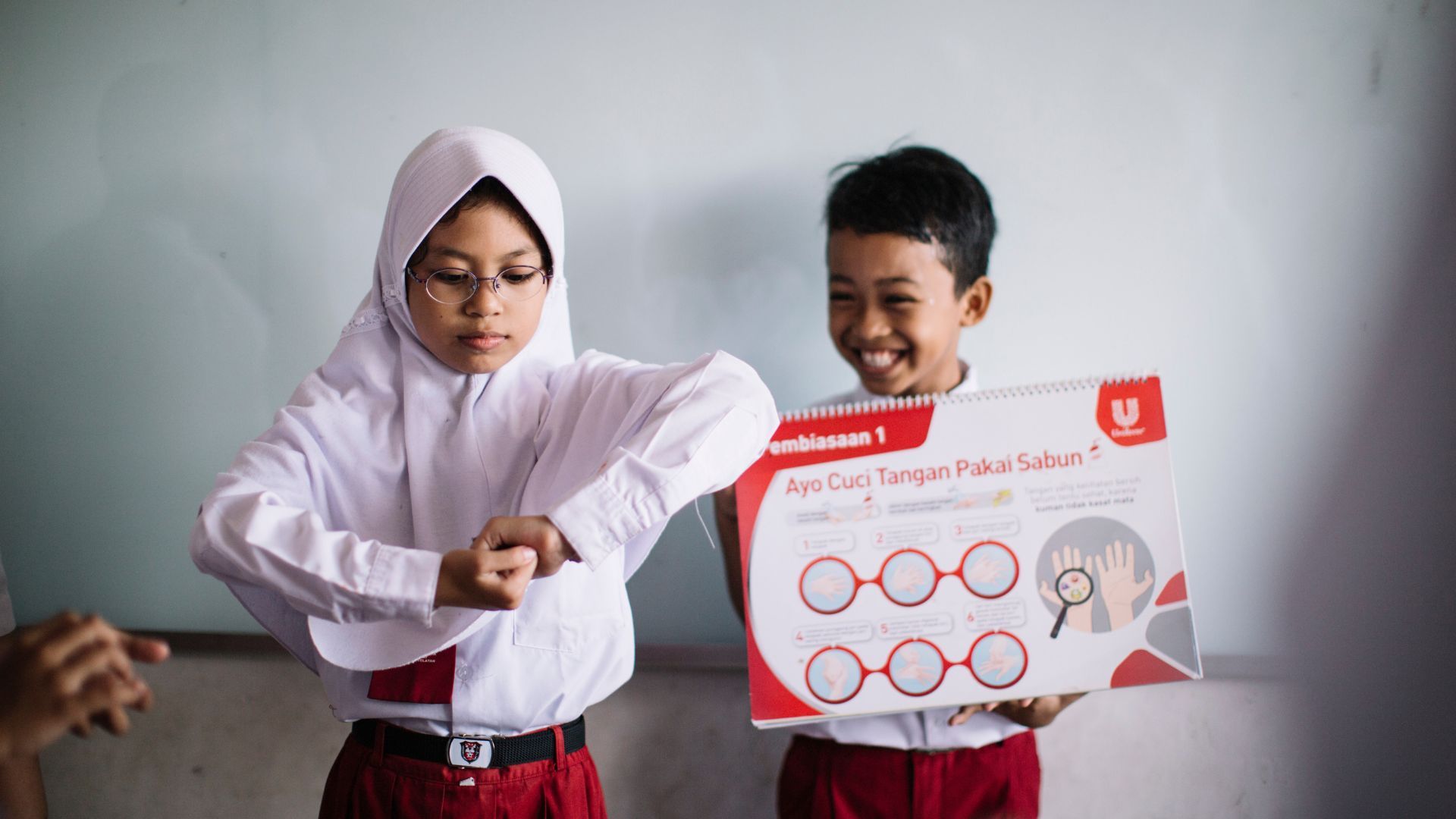 Anak-anak berlatih mencuci tangan di lingkungan kelas.