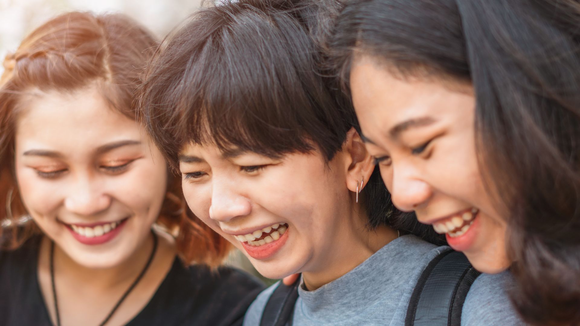Three friends smiling and laughing together.