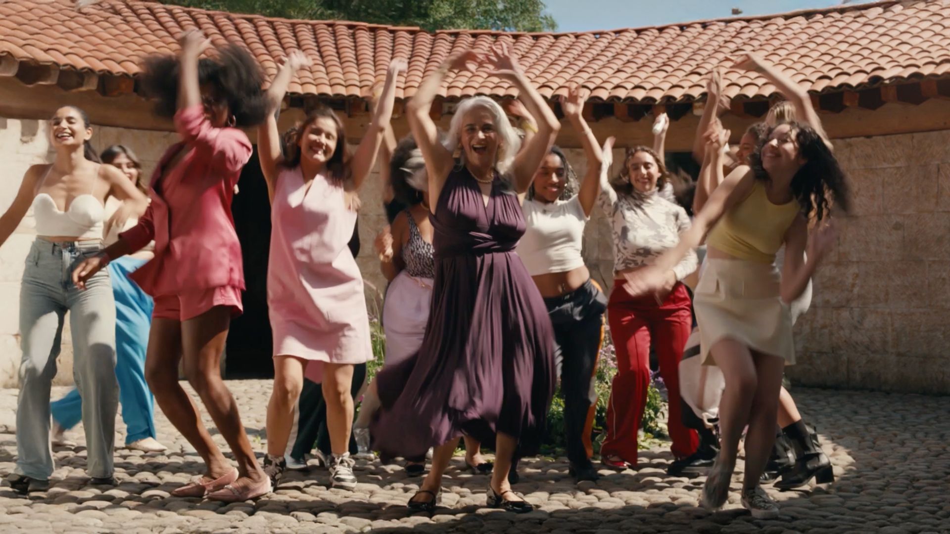 Sekelompok orang menari dengan gembira di luar ruangan.