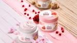 Dove body scrub jars arranged with pink flowers, pomegranate seeds, and sugar cubes.